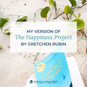 The Happiness Project book by Gretchen Rubin on beach with light sand and vegetation